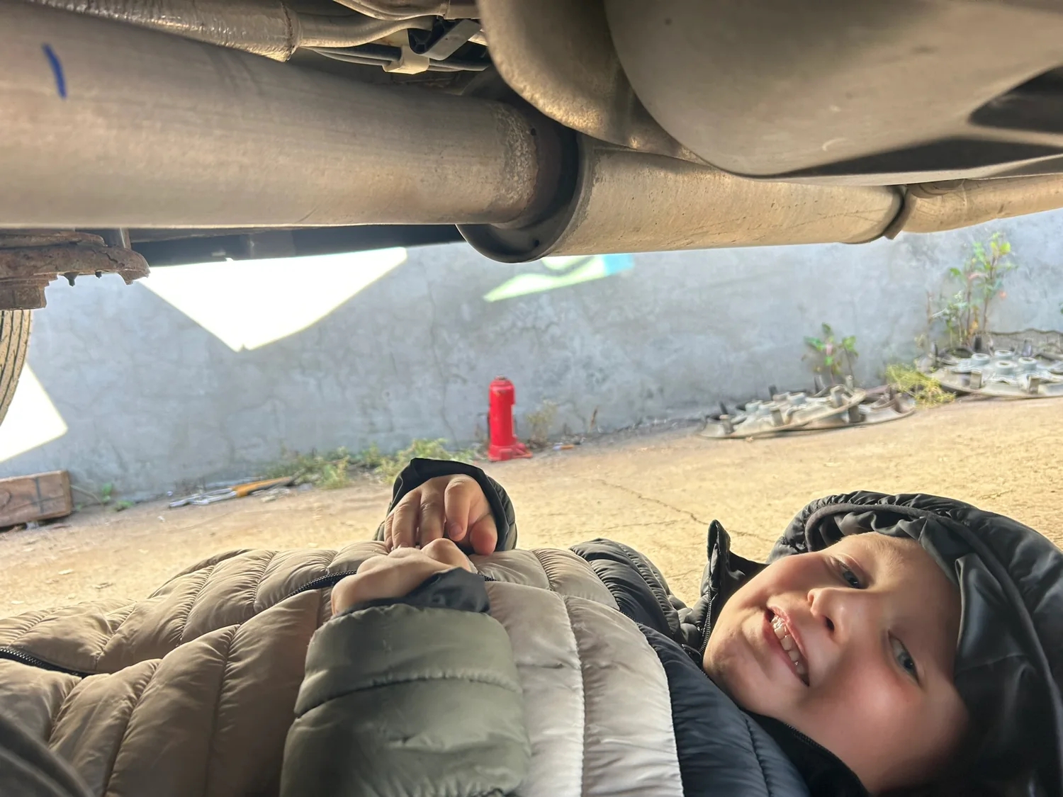 Elijah bundled up underneath a parked vehicle in the family driveway